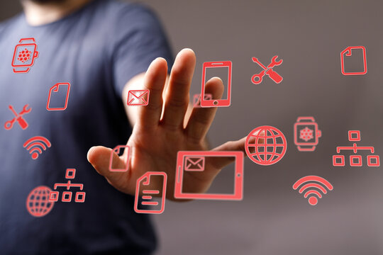 Hand reaching towards digital network of icons representing technology, communication, and connectivity. Modern