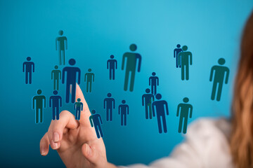Hand touching human icons symbolizing people, teamwork, connection, and social networks on a blue background. I