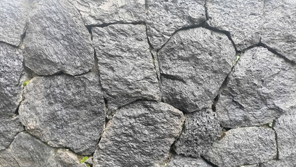 Rough and irregular surface texture of dark gray stone paving blocks, ideal for background.
