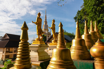 Golden Buddha statues and gleaming stupas stand in the foreground, offering a spiritual and scenic...