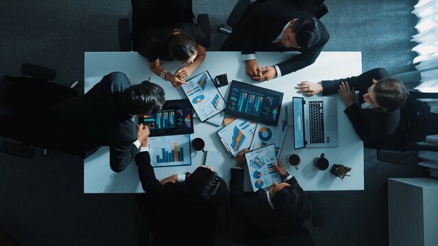 Top down aerial view of professional businessman handed out financial statistic to analyst data investment graph. Group of diverse investors brainstorming and planning marketing strategy. Directorate. - Powered by Adobe