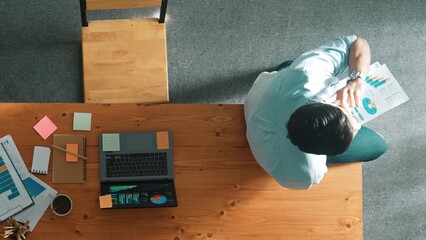 Top down view of businessman talking phone with team while sitting on table. Smart manager speaking and calling with colleague about marketing strategy while looking at financial graph. Convocation.