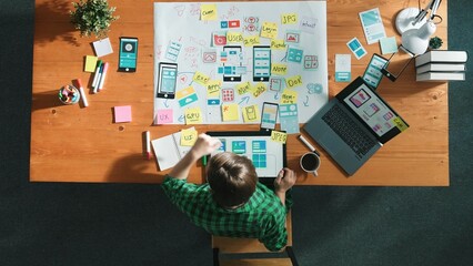 Top view of smart developer working on tablet and writing Ux Ui design for mobile phone interface...