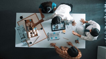 Top down view of architect engineer team discussing and point at tablet display construction at table with blueprint and house model at meeting. Diverse designer planning design house. Alimentation. © InfiniteFlow