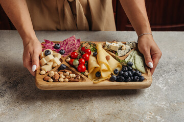 serving different snacks from salami and cheese on a wooden board for alcohol