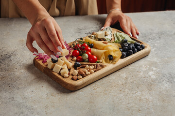 serving different snacks from salami and cheese on a wooden board for alcohol