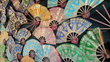 Arrangement of traditional hand fans with various bright motifs and colors.
