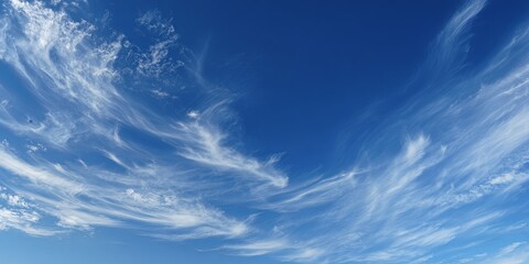 Wispy cirrus clouds stretching across deep blue sky, minimalism, clean atmospheric design.