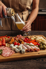 serving different snacks from salami and cheese on a wooden board for alcohol
