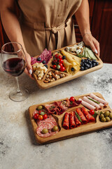serving different snacks from salami and cheese on a wooden board for alcohol