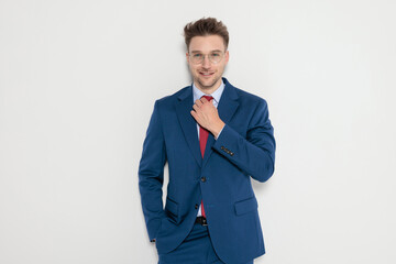 Smiling handsome man in suit adjusting tie