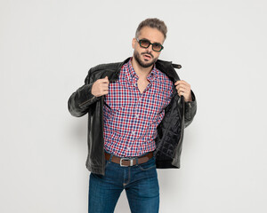 Attractive man opening his leather jacket and posing