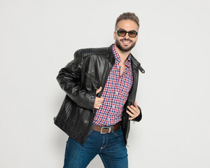Happy smiling man fixing his leather jacket
