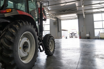 Agricultural tractor inside service garage, modern farm equipment storage and maintenance concept,...