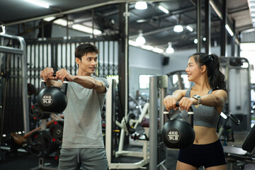 Fit and muscular man and woman focused on lifting a kettlebell during an exercise class