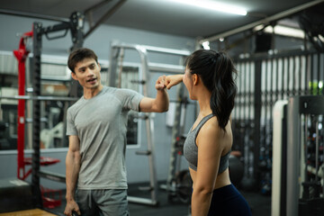 Obraz premium A trainer and woman greeting with a fist bump in the gym
