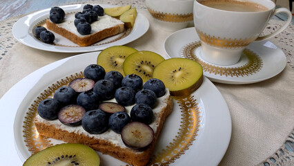 Healthy breakfast toast with blueberries, kiwi and coffee. 