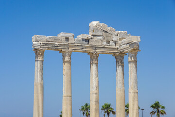Fototapeta premium An ancient structure Apollon Temple in the form of many pillars and an arch embedded in the side of Turkey In the background is the blue Mediterranean Sea. The sky is bright and blue