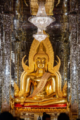 Obraz premium Inside the glass temple at Wat Tha Sung, Uthai Thani Province, Thailand, the room is illuminated with dazzling light, with a golden Buddha image at its center.