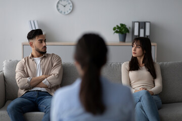 In a counseling clinic, a female psychologist guides an arab couple through a therapy session. The...