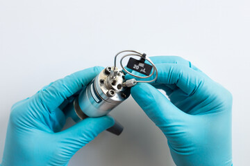 A scientist in blue gloves installs a 20 µL sample loop onto a manual HPLC injector valve. Close-up of component assembly for high performance liquid chromatography in a science lab.