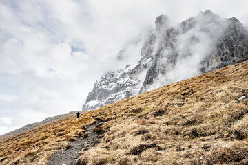 Hiker Climbs Uphill Toward The North Face Of The Eiger In Autumn