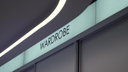 Modern illuminated wardrobe sign on a minimalist interior wall with clean architectural lines and bright contemporary lighting in a stylish public or commercial space
