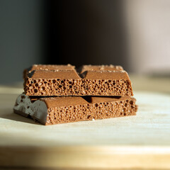 A stack of milk chocolate in a close-up shot. Sweet milk chocolate with a visible texture and air bubbles, captured in detailed close-up
