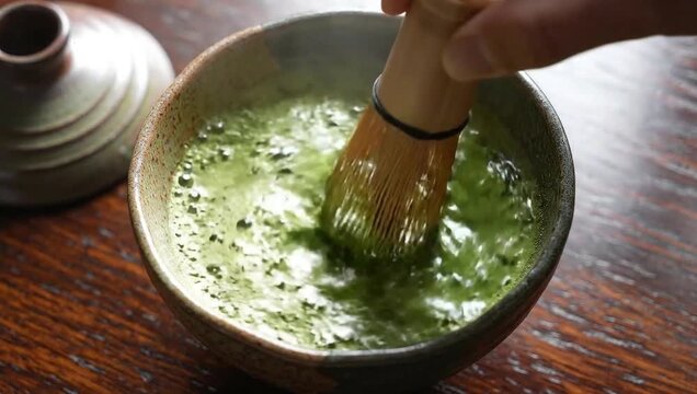 Ceremonial Matcha Tea: A close-up shot captures the delicate whisking of vibrant green matcha powder, blending it into a frothy elixir of traditional wellness.