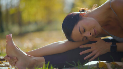 Woman focusing on a seated forward bend pose on a yoga mat, gently stretching her body and finding...
