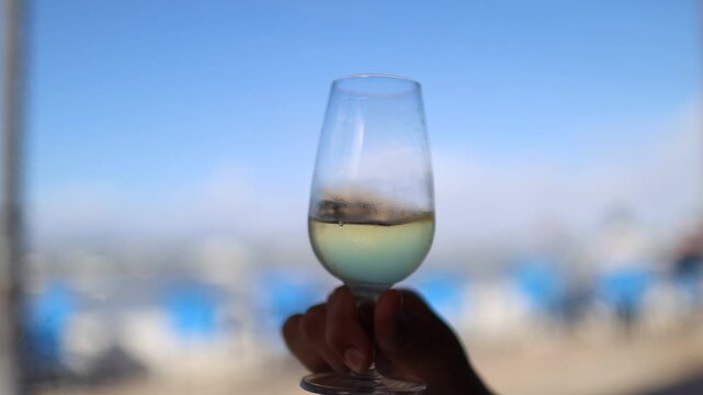 Hand swirling manzanilla wine in a glass at the beach
