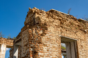 A heavily damaged red brick wall, background with the texture of an old red brick wall and plaster elements