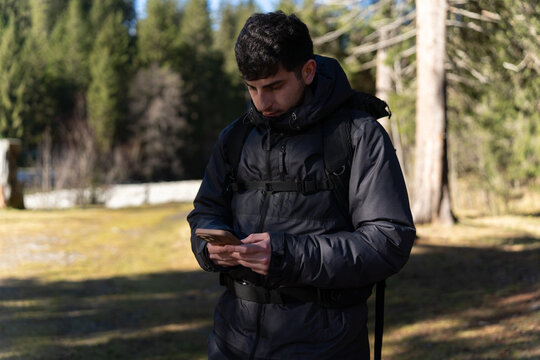 Young hiker using smartphone in nature looking for directions