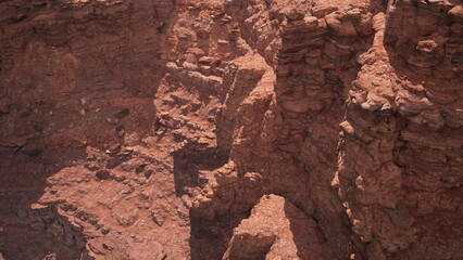 Deep canyons and jagged cliffs create a breathtaking landscape of red rock formations, illuminated by the warm glow of sunlight. Nature showcases its raw beauty in this unique geological wonder.