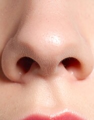 Fototapeta premium Close-up of a human nose, nostrils visible, against a skin backdrop