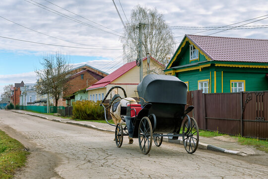 Rear view of a horse-drawn carriage with a closed black awning on the street. Village of Vyatskoye.