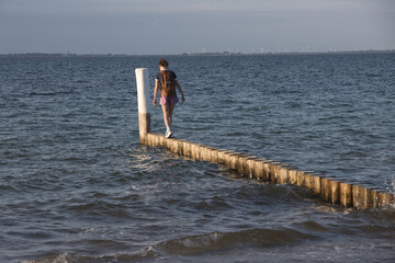 Frau balanciert auf Holzbohlen am Ostseestrand bei Heiligenhafen