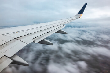 Airplane wing flying above a cloudy sky