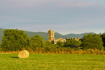 Rural landscape with hay bale and medieval Ainsa town