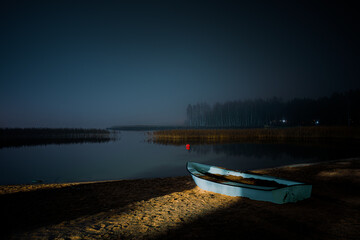 Small Boat on a Sandy Beach Illuminated by Light at Night in Raisio, Finland.
