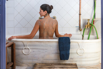 Woman enjoying clay treatment in a bathtub at a hot springs spa