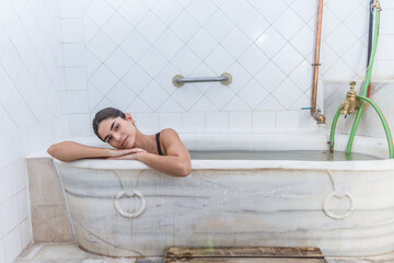 Woman relaxing in a marble bathtub at a thermal spa