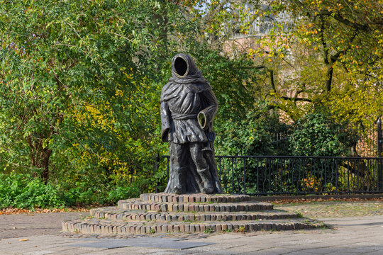 A bronze statue of Thonis van Grol, also known as Drogenap, a historic figure from Zutphen, standing veiled on a brick pedestal.