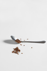 Flax seeds in a silver spoon on a white background