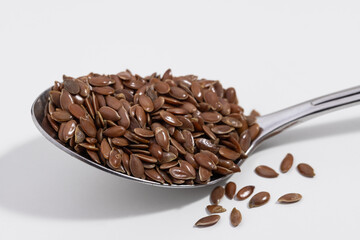 Flax seeds in a silver spoon on a white background