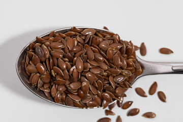 Flax seeds in a silver spoon on a white background