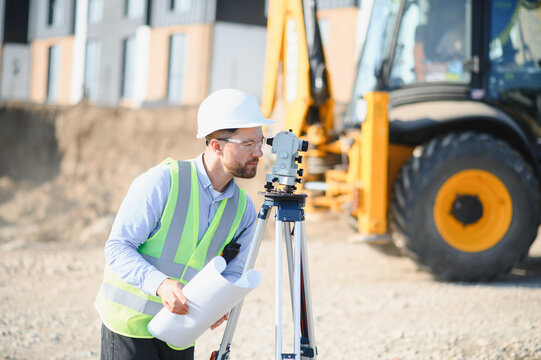 Surveyor using optical level checking construction site blueprint