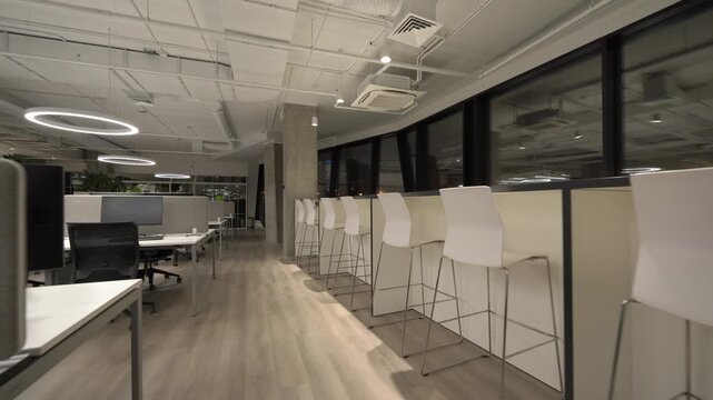 Modern empty office interior with panoramic windows and circular LED ceiling lights, captured with a smooth forward-moving camera in a clean contemporary workplace during evening hours