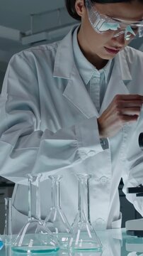 Chemist conducts research, Asian scientist performs precise titration experiments, Modern laboratory environment with scientist performing detailed titration of vibrant chemical mixtures