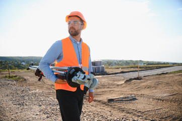 Surveyor engineer carrying land surveying equipment at construction site